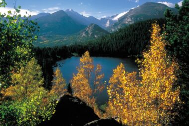 A view of a lake and the mountain range in Rocky Mountain National Park just as the leaves are starting to change color.