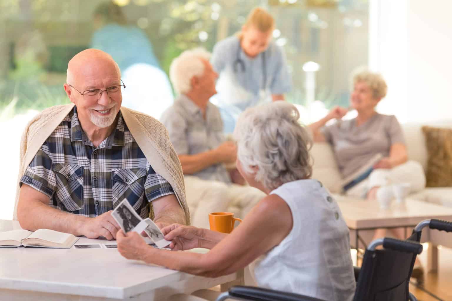 Married couple of elders sitting together and watching old photos at senior living community. Photo: Adobe Stock